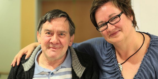 Eine Pflegerin legt liebevoll den Arm um einen Bewohner