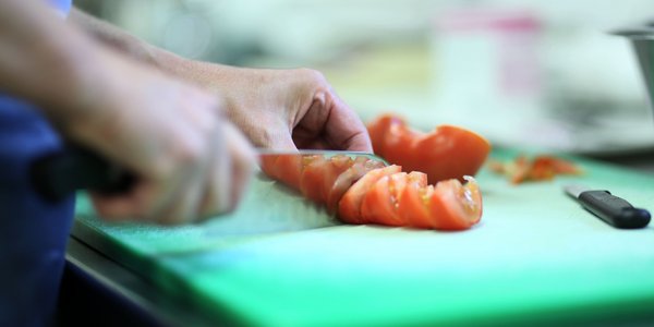 Der Koch schneidet frische Tomaten in der Küche des Seniorencentrums