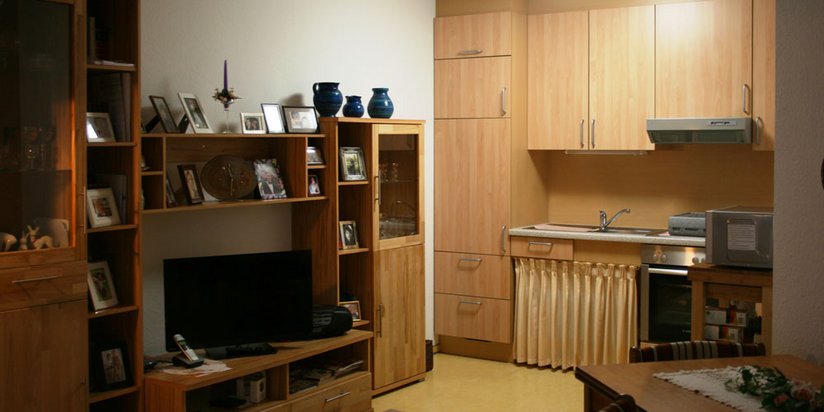 Bewohnerzimmer mit Kochnische und Fernsehwand 