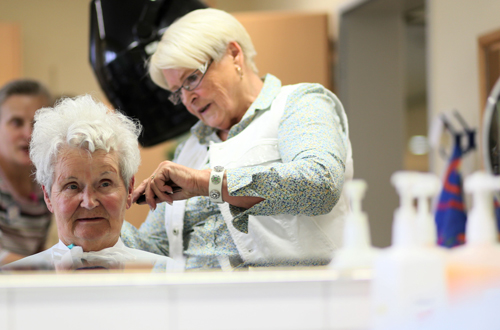 Eine Friseurin richtet die Haare einer Bewohnerin