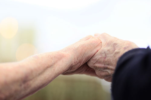 Zwei Senioren halten einander die Hand